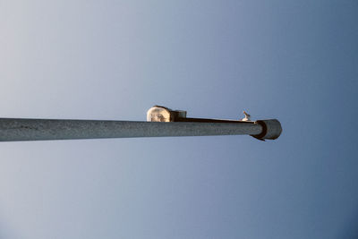 Low angle view of cross on street against clear blue sky