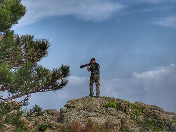 Low angle view of man standing on rock against sky