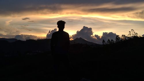 Silhouette man standing on mountain against sky during sunset