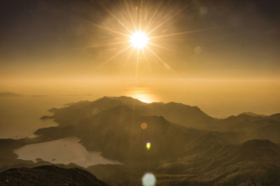 Sun shining through clouds over mountains