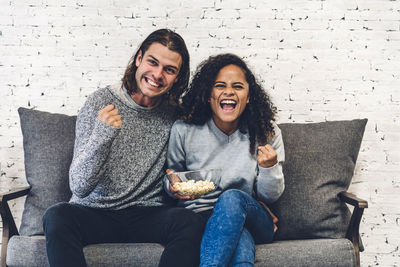 Portrait of cheerful couple sitting on sofa at home