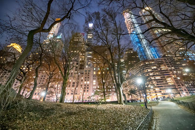 Illuminated street amidst buildings in city at night