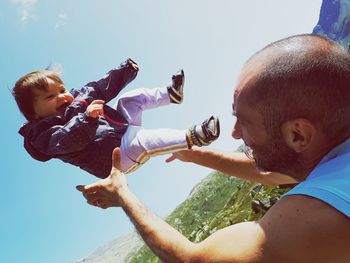 Father and daughter against sky