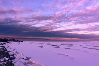 Scenic view of sea against dramatic sky during sunset