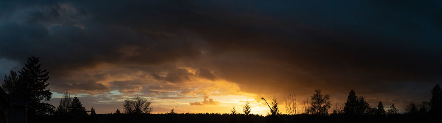 Low angle view of silhouette trees against dramatic sky