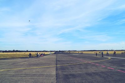 People at airport runway against sky