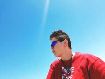 Low angle view of woman in sunglass against clear blue sky