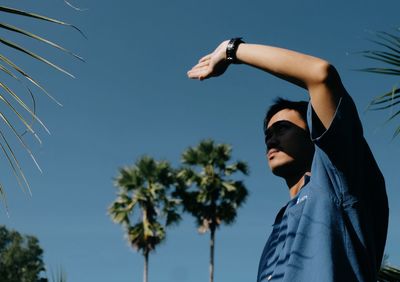 Low angle view of young man against blue sky