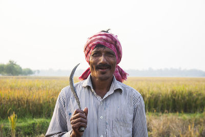 Portrait of man standing on field against sky