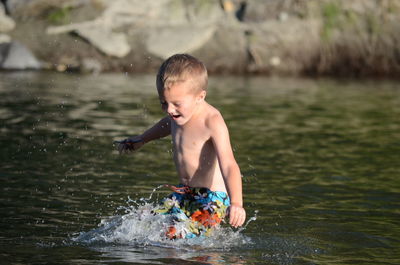 Shirtless boy playing in water outdoors