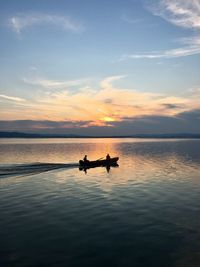 Silhouette man on boat in sea against sky during sunset