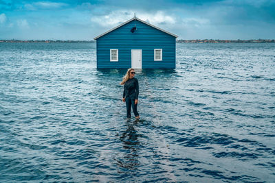 Full length of boy standing in sea against sky