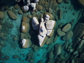 Drone shot of woman relaxing on rock at lake tahoe on sunny day