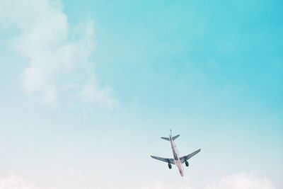 Low angle view of airplane flying against blue sky