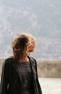 Young woman with tousled hair looking away while standing outdoors