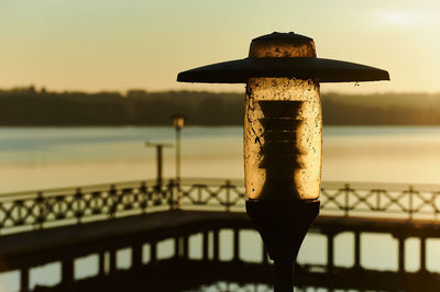 Close-up of railing against sea during sunset