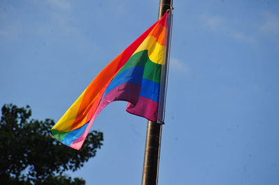 Low angle view of rainbow flag against blue sky