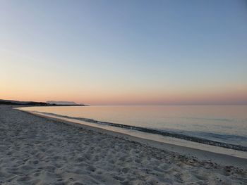 Scenic view of beach against clear sky during sunset