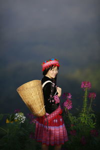 Midsection of woman holding bouquet against red wall