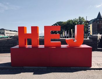 Red text on building against sky on sunny day