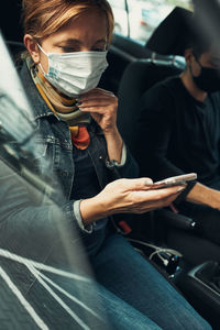 Woman using mobile phone sitting in bus