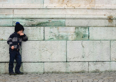 Boy standing on brick wall