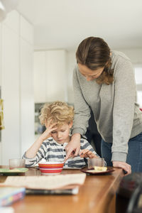 Woman and boy using digital tablet at dining table in living room