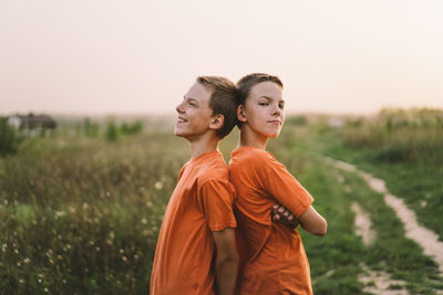 Funny twin brother boys playing outdoors on field at sunset.