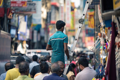 Rear view of people walking on street in city