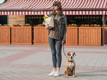 Full length of young woman standing with dog on street