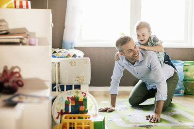 Boy riding on father's back while playing at home