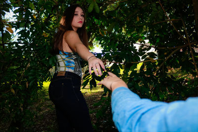 Cropped hand of friend reaching towards young woman on field