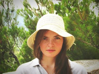 Portrait of young woman wearing hat against trees