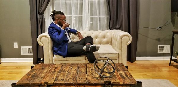 Side view of young man sitting on sofa at home