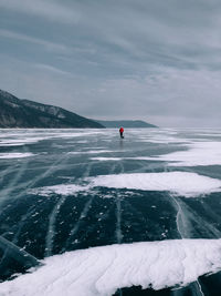 Rear view of man walking on frozen lake