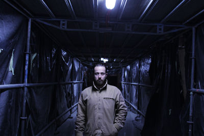 Portrait of young man standing in illuminated room