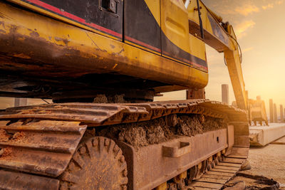 Closeup dirt track pad of backhoe. digger parked at construction site. bulldozer near concrete pole. 