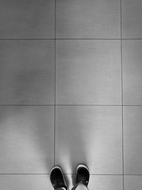 Low section of man standing on tiled floor