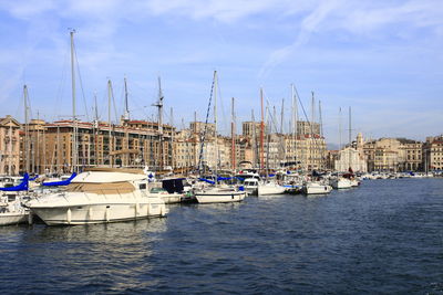 Sailboats moored at harbor against sky