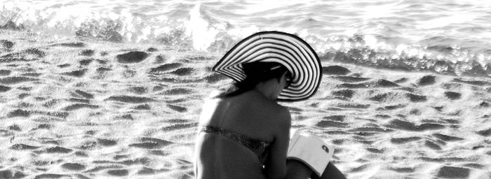 Woman in sun hat sitting at beach
