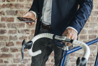Close-up of businessman with bicycle checking cell phone