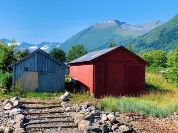 House on field by mountain against sky