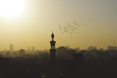 Silhouette mosque and cityscape against sky