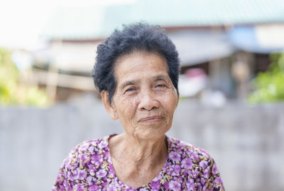 Old asian woman's face with wrinkles elderly senior smiling happiness looking at the camera. 