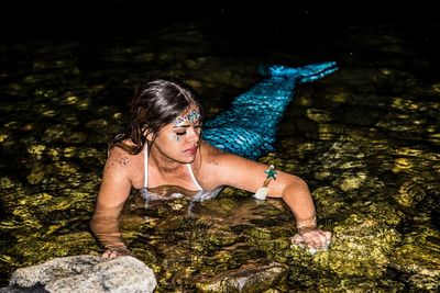 High angle view of mermaid swimming in lake at dusk