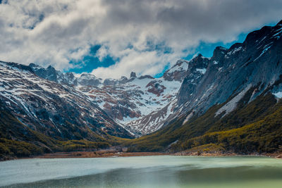 Scenic view of lake by snowcapped mountains against sky