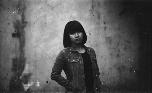 Portrait of young woman standing against wall