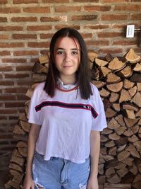 Portrait of young woman standing against wall