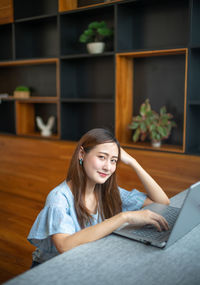 Young woman using mobile phone while sitting on table