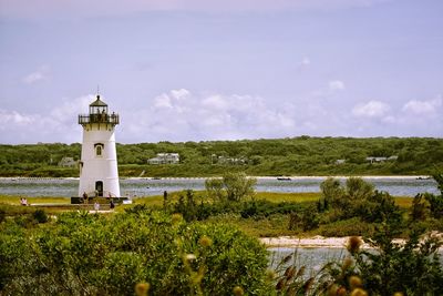 Lighthouse by building against sky